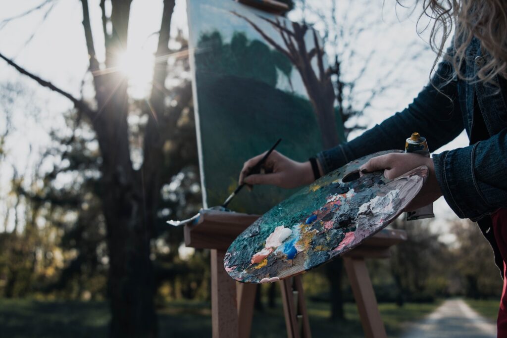 Femme étant un pinceau devant un tableau. La créativité est une façon d’exprimer les parties les plus intimes de soi